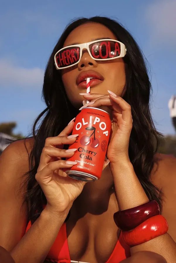 Femme dégustant une canette Olipop Cherry Cola – soda sain prébiotique naturel