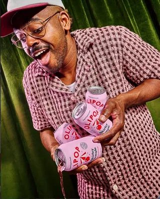 Homme souriant avec canettes Olipop Shirley Temple – alternative naturelle au sucre soda sain